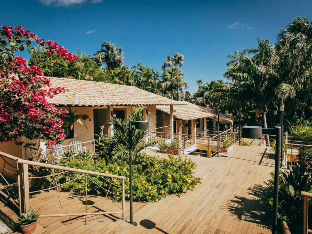 Sunny outdoor area of a rustic inn with a flowery garden, wooden ramps, and stairs connecting the room balconies. Sunny outdoor area of a rustic inn with a flowery garden, wooden ramps, and stairs connecting the room balconies.