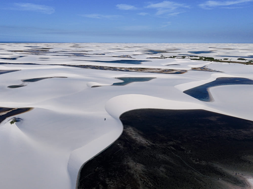 A wide landscape shows thousands of rainwater lagoons interspersed among the white sand dunes. A wide landscape shows thousands of rainwater lagoons interspersed among the white sand dunes.
