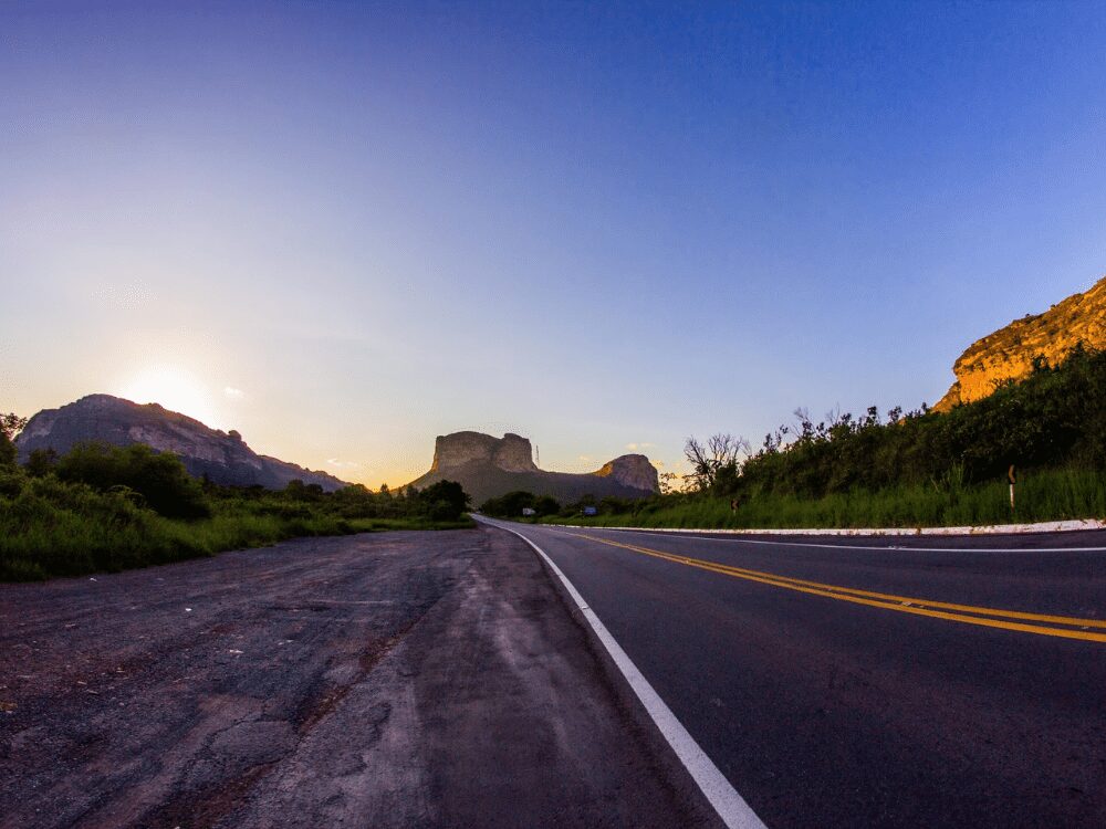 An empty paved road leads directly toward the iconic Morro do Pai InĂĄcio mountain under a clear blue sky at dusk. An empty paved road leads directly toward the iconic Morro do Pai InĂĄcio mountain under a clear blue sky at dusk.