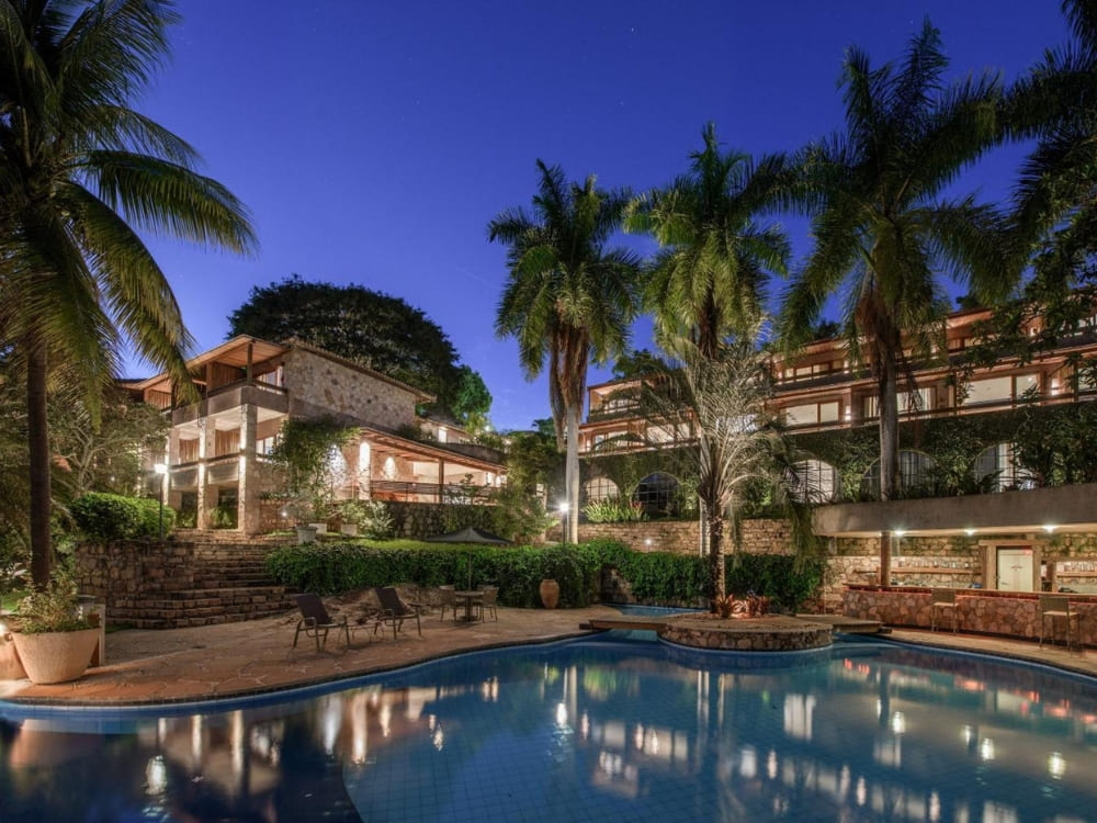  Illuminated swimming pool and tropical palm trees at night at Hotel Canto das Águas in Lençóis. 
