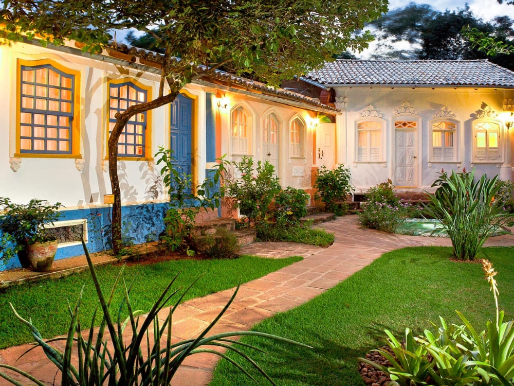 Colonial-style courtyard of Pousada Vila Serrano in Lençóis featuring blue and white walls and lush green gardens. 