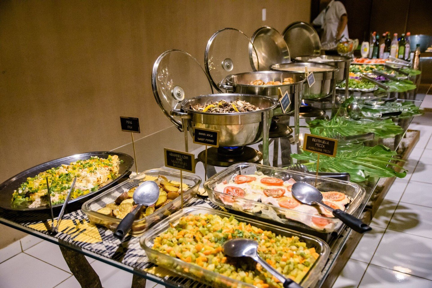 Een uitgebreid dinerbuffet in een lodge voor een budget Pantanal tour, met bewegwijzerde gerechten zoals zoete aardappel, aubergine pizza, gemengde groenten, vis en verse salades warm gehouden in chafers