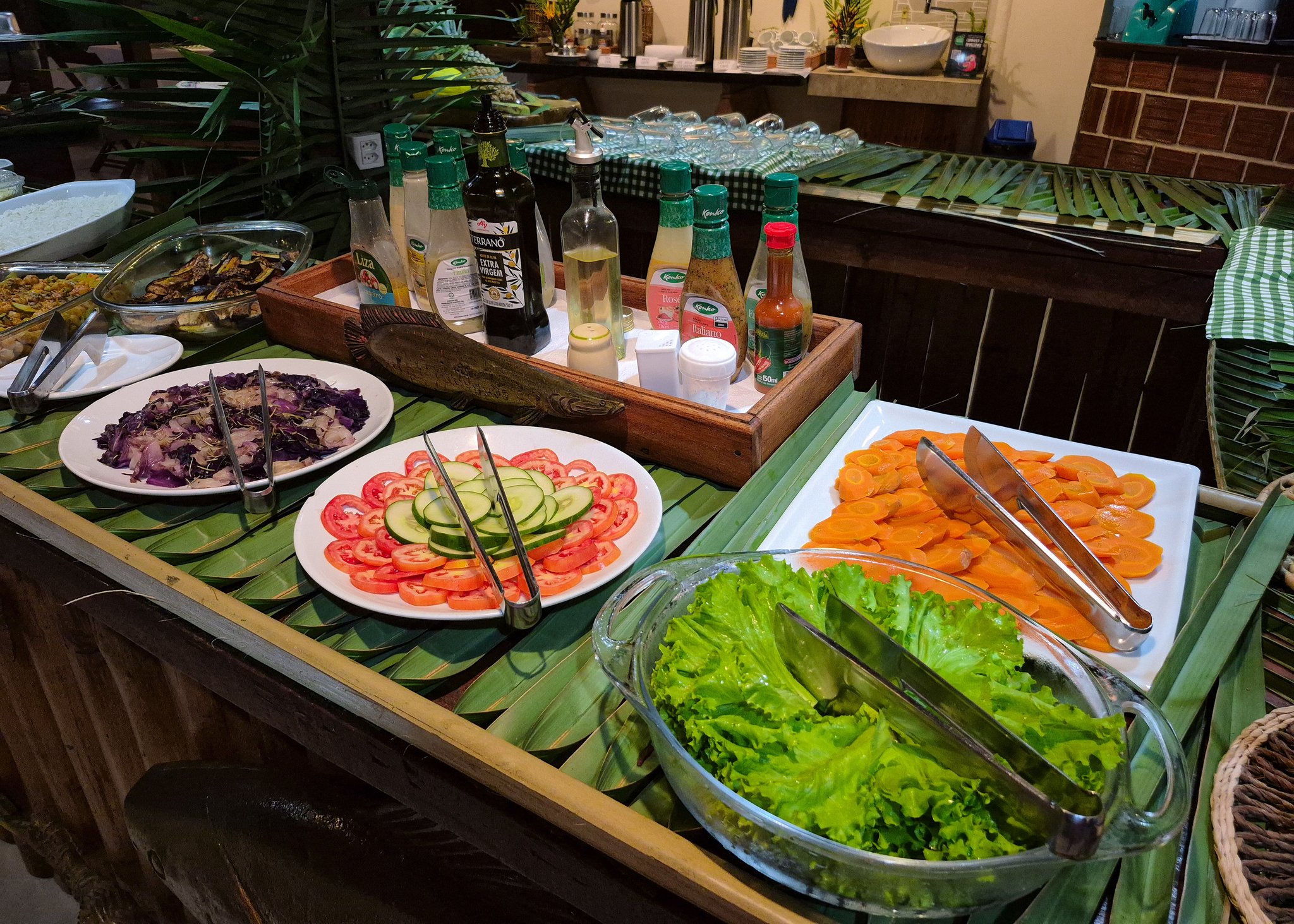 Goed eten midden in de jungle, het kan gewoon. Een kleurrijk saladebuffet in de Amazon Turtle Lodge, met borden gesneden tomaten, komkommer, wortels, rode kool en knapperige sla op bananenbladeren naast dressings en olijfolie