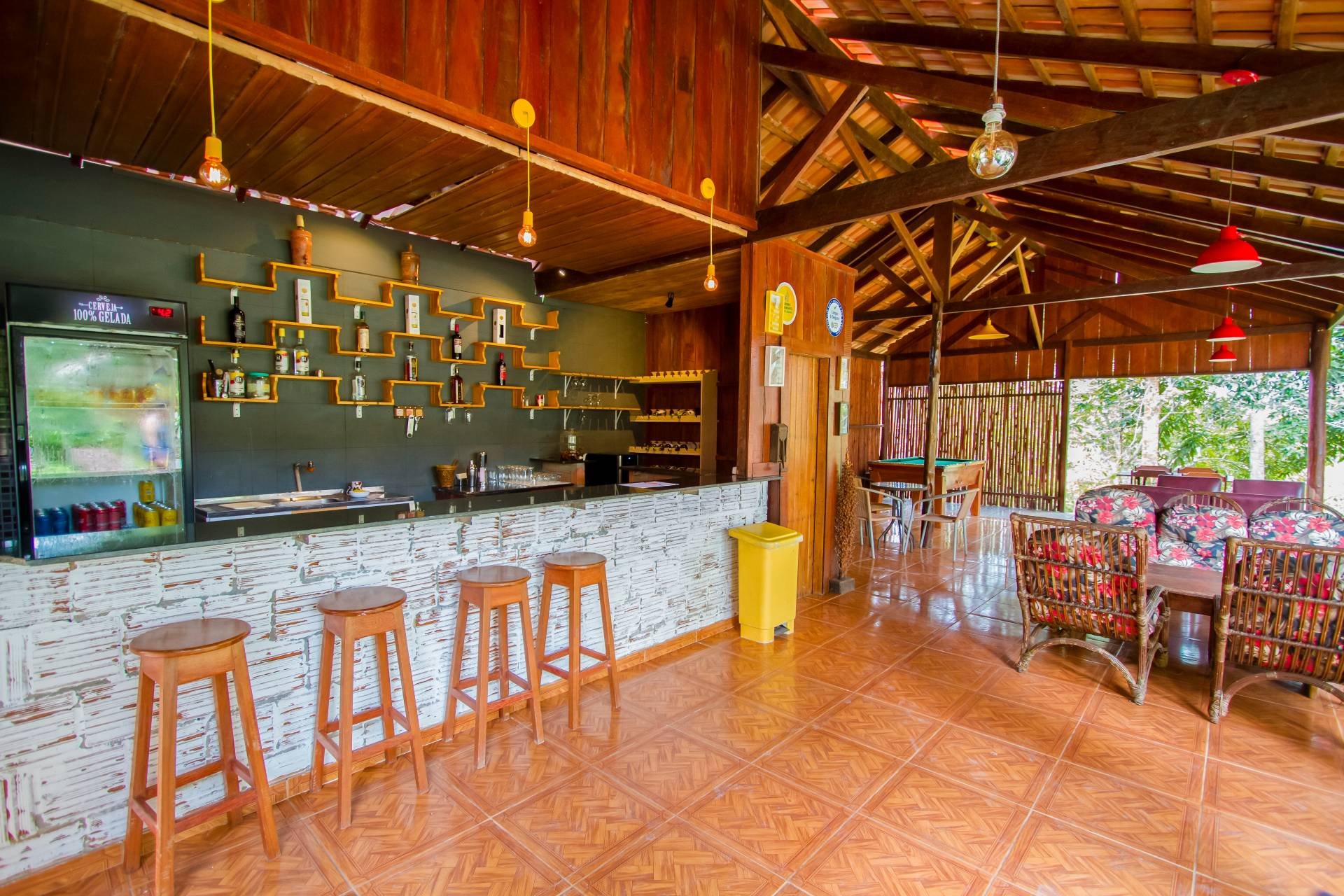 Een koud glas, een houten kruk, de jungle om de hoek. Zo eindigt een dag op het water. De openluchtbar van de Amazon Turtle Lodge met een witgepleisterde stenen toonbank, houten barkrukken, verspringende flessenplanken en een hoog houten dakgebinte dat uitkijkt op weelderig groen.