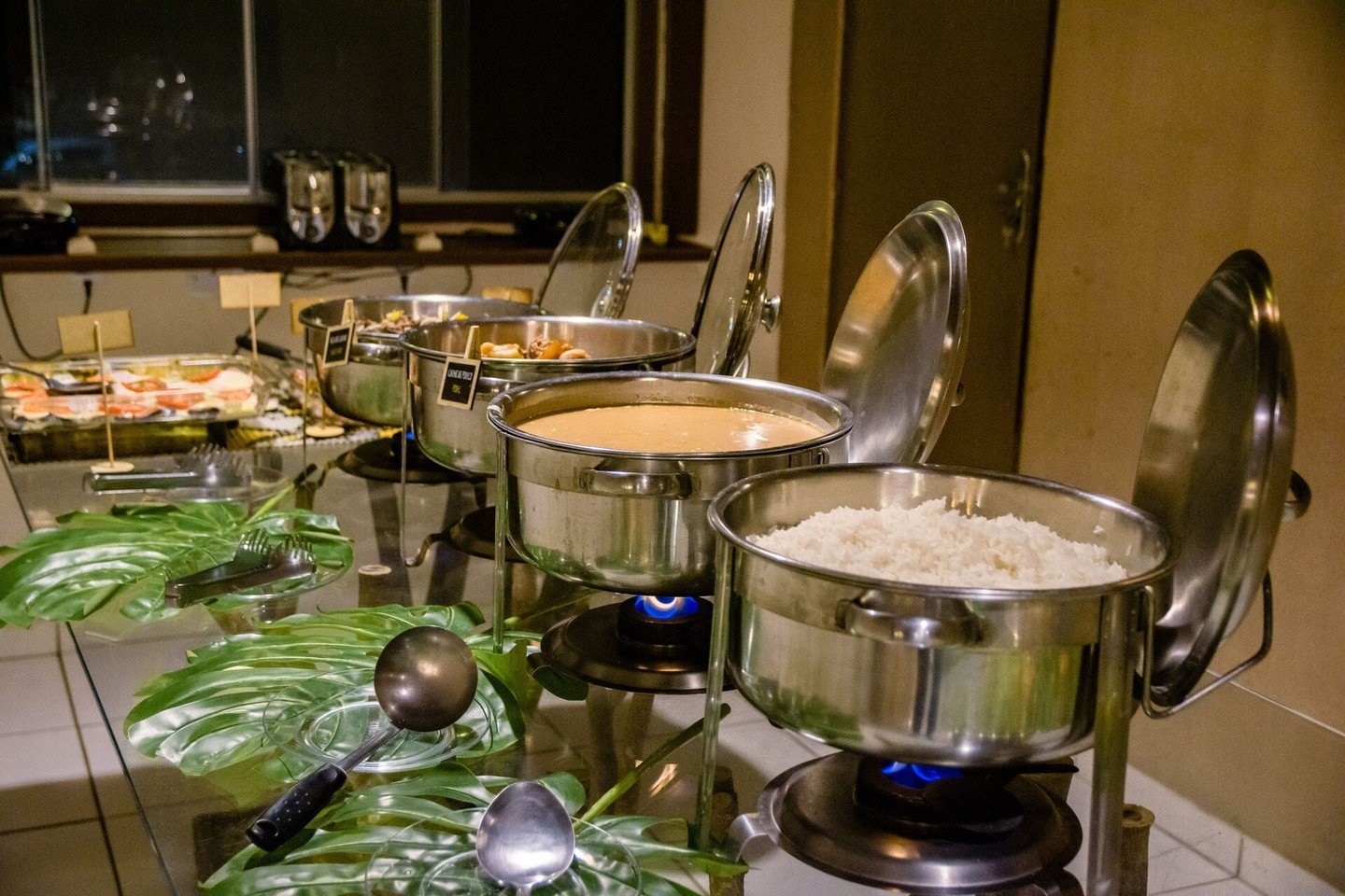 Roestvrijstalen chafing dishes met rijst en een warme saus op blauwe vlammen bij een buffetdiner in een Pantanal-lodge, inbegrepen in de all-inclusive budgettrip