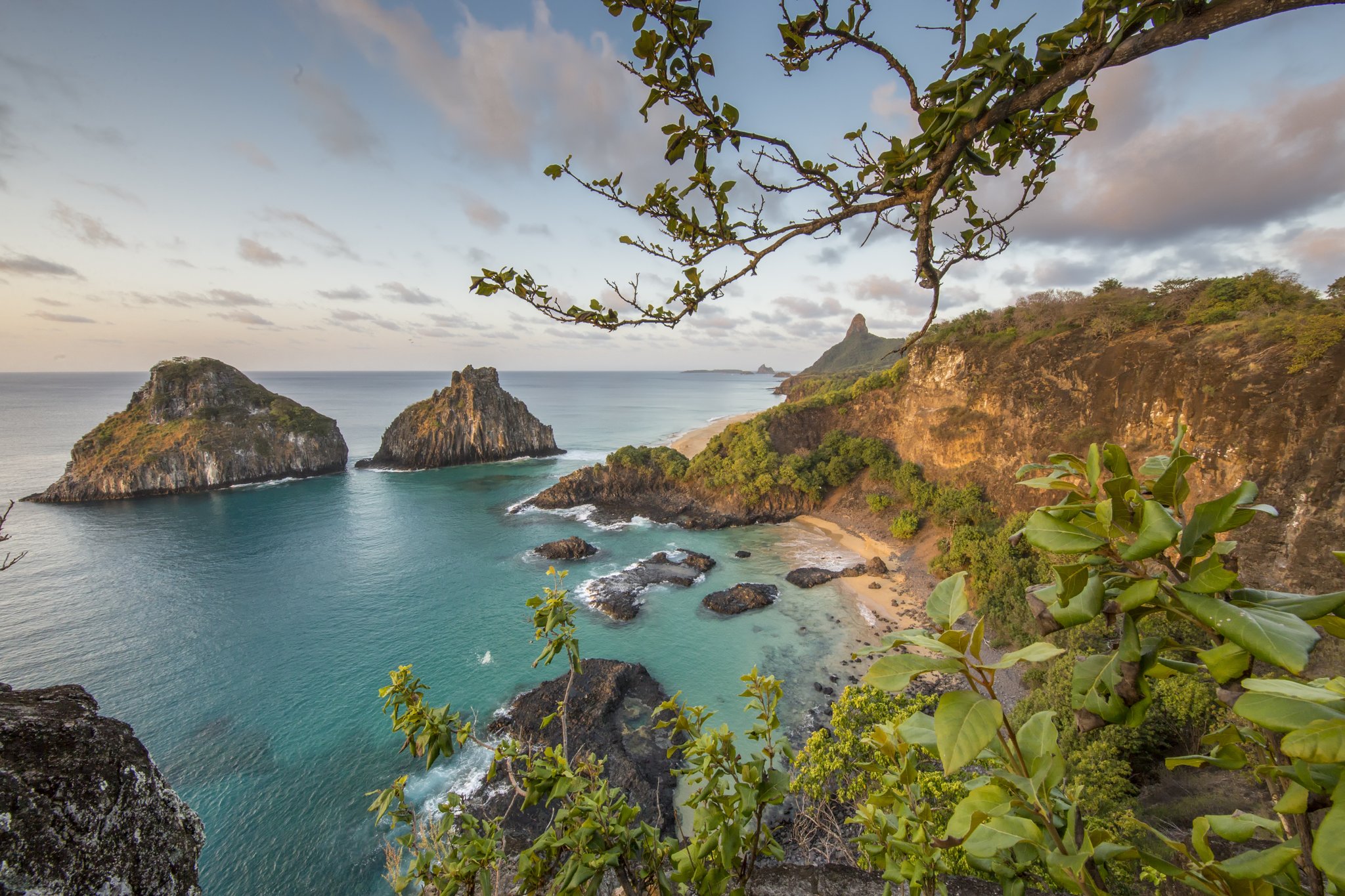 Aerial view of turquoise coves, golden cliffs and twin rock islets framing the coastline of Fernando de Noronha, the setting for a 2-Day Diving Package in Fernando de Noronha
