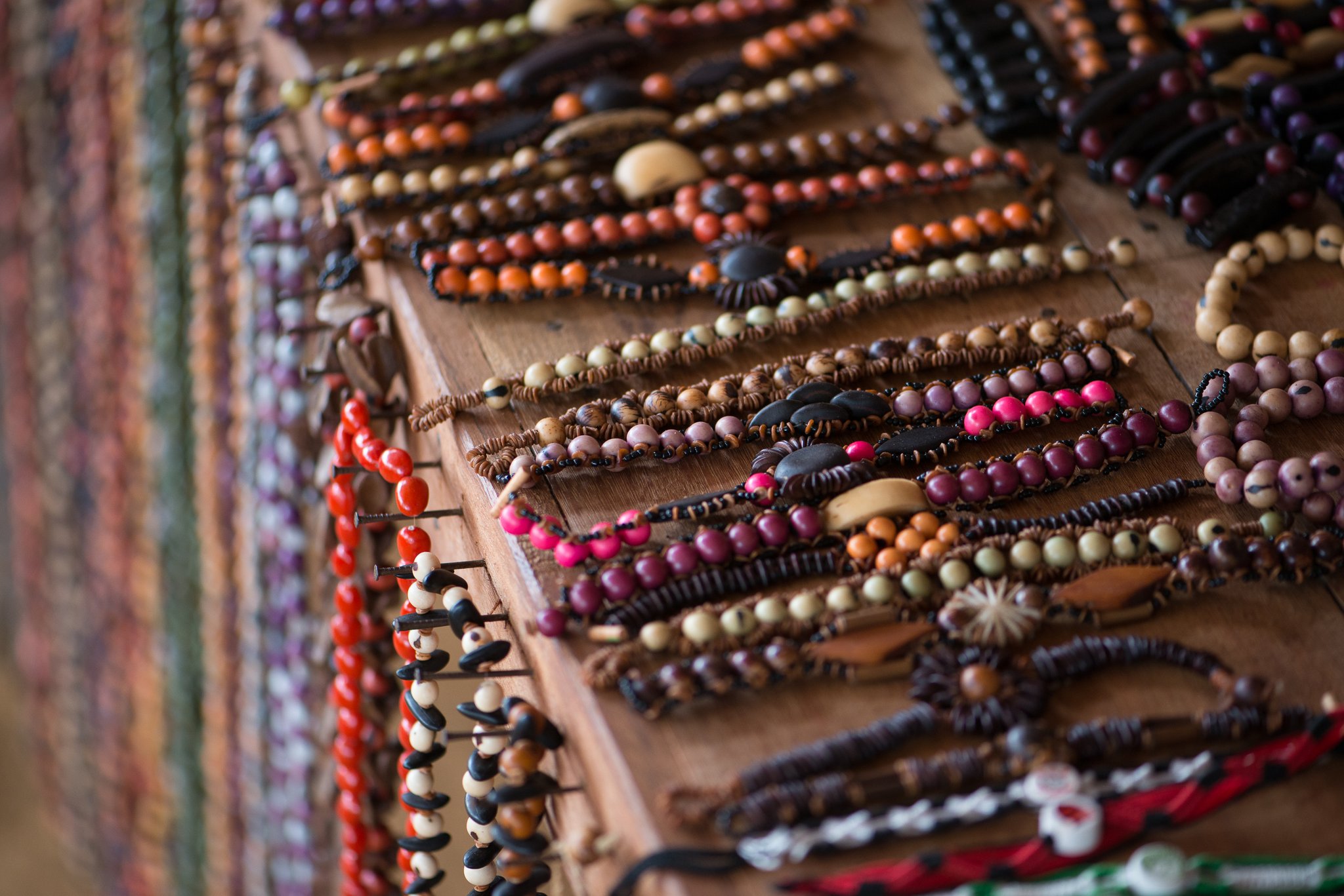 Rows of handmade bracelets strung with colourful natural seeds and wooden beads displayed on a wooden board at a riverside community near Anavilhanas Jungle Lodge Brazil