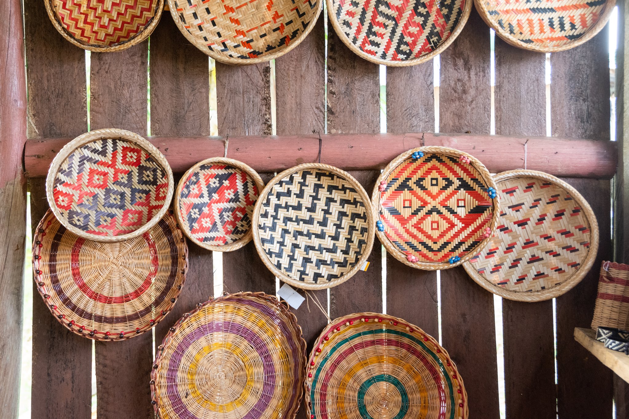 A wall of colorful handwoven round baskets with geometric and concentric patterns displayed at a riverside community near Anavilhanas Jungle Lodge Brazil