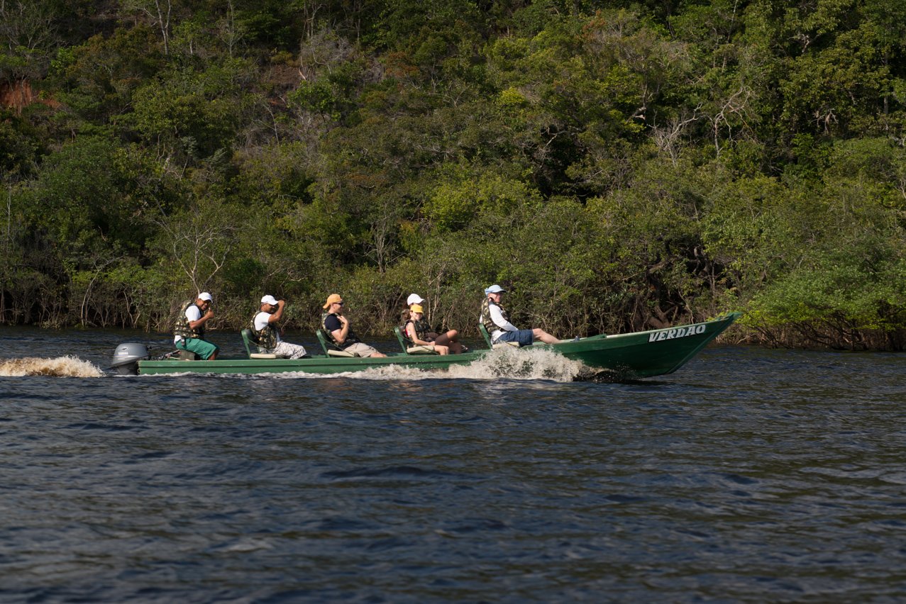 Full throttle into the heart of the Amazon. Photo: MARCELO ISOLA A group of ecotourists in life jackets speeds along the Rio Negro aboard a green motorboat during an Anavilhanas Jungle Lodge Brazil expedition, with dense riparian forest lining the far bank