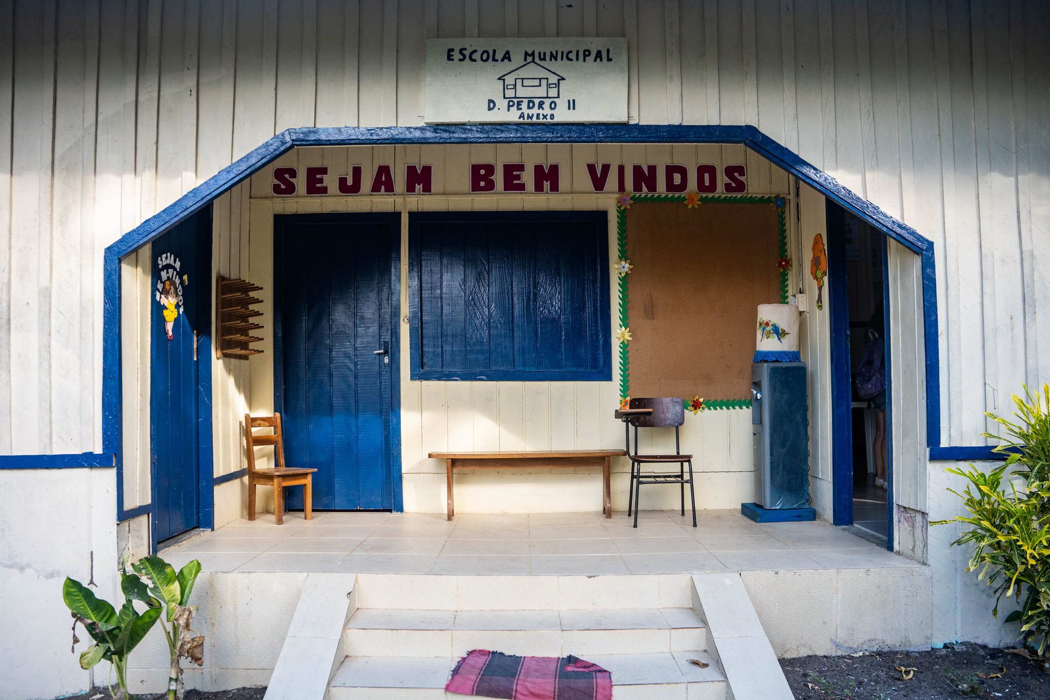 Entrance of Escola Municipal D. Pedro II, a white wooden community school with blue trim and a 'Sejam Bem Vindos' welcome sign, visited during an Anavilhanas Jungle Lodge Brazil riverside community excursion