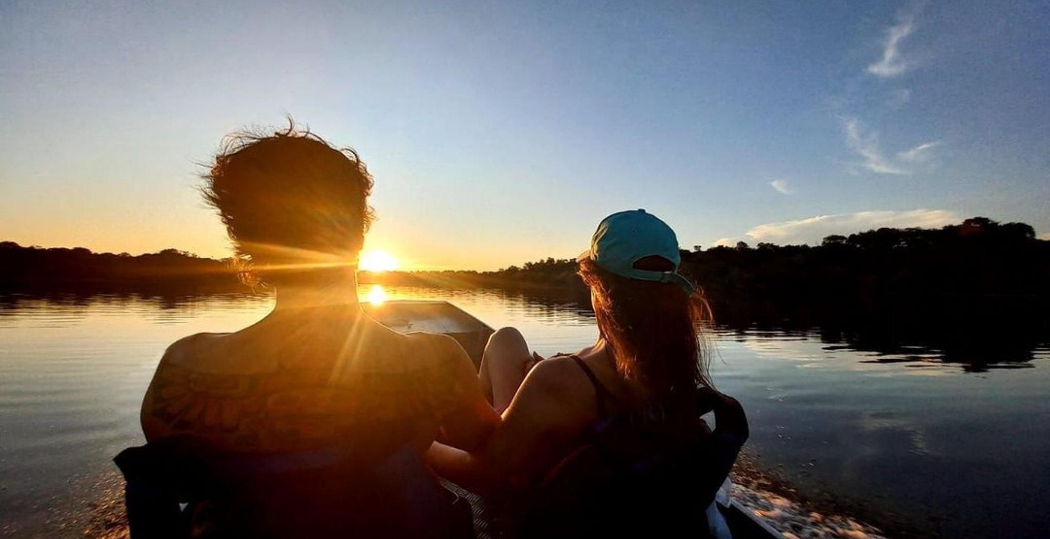 Couple watching the sunset from a canoe on a calm river during a Brazilian Amazon jungle tour