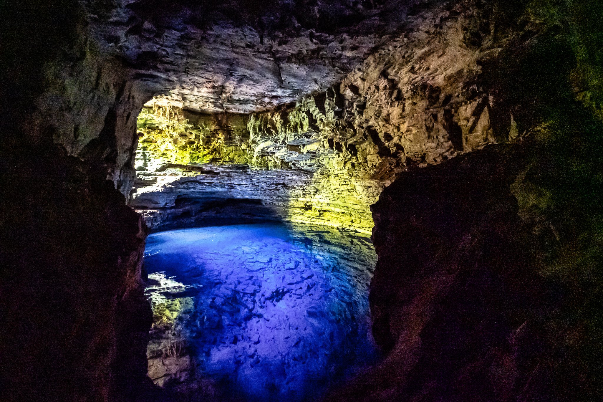 Electric blue and yellow lights illuminate a subterranean pool inside a limestone cave on a Chapada Diamantina tour in Brazil