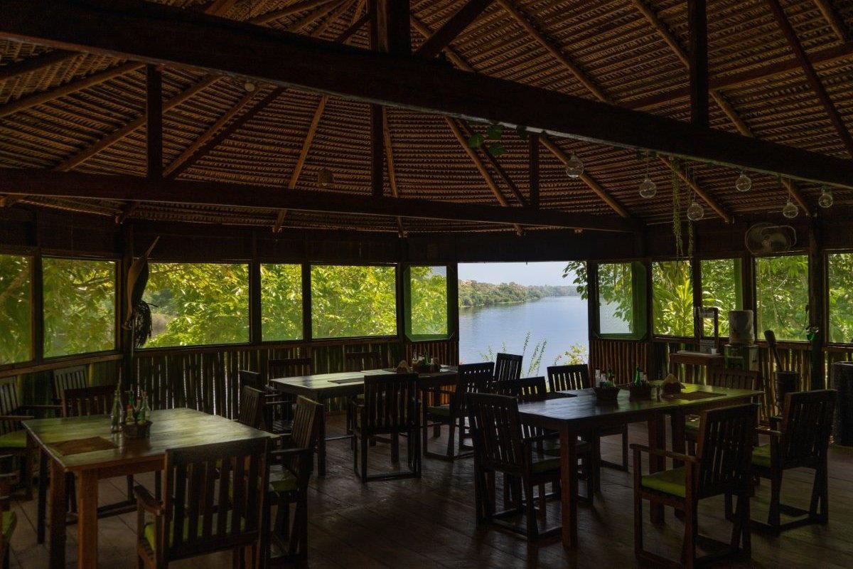 Open-sided wooden dining hall at Dolphin Lodge framing a wide river view between the trees