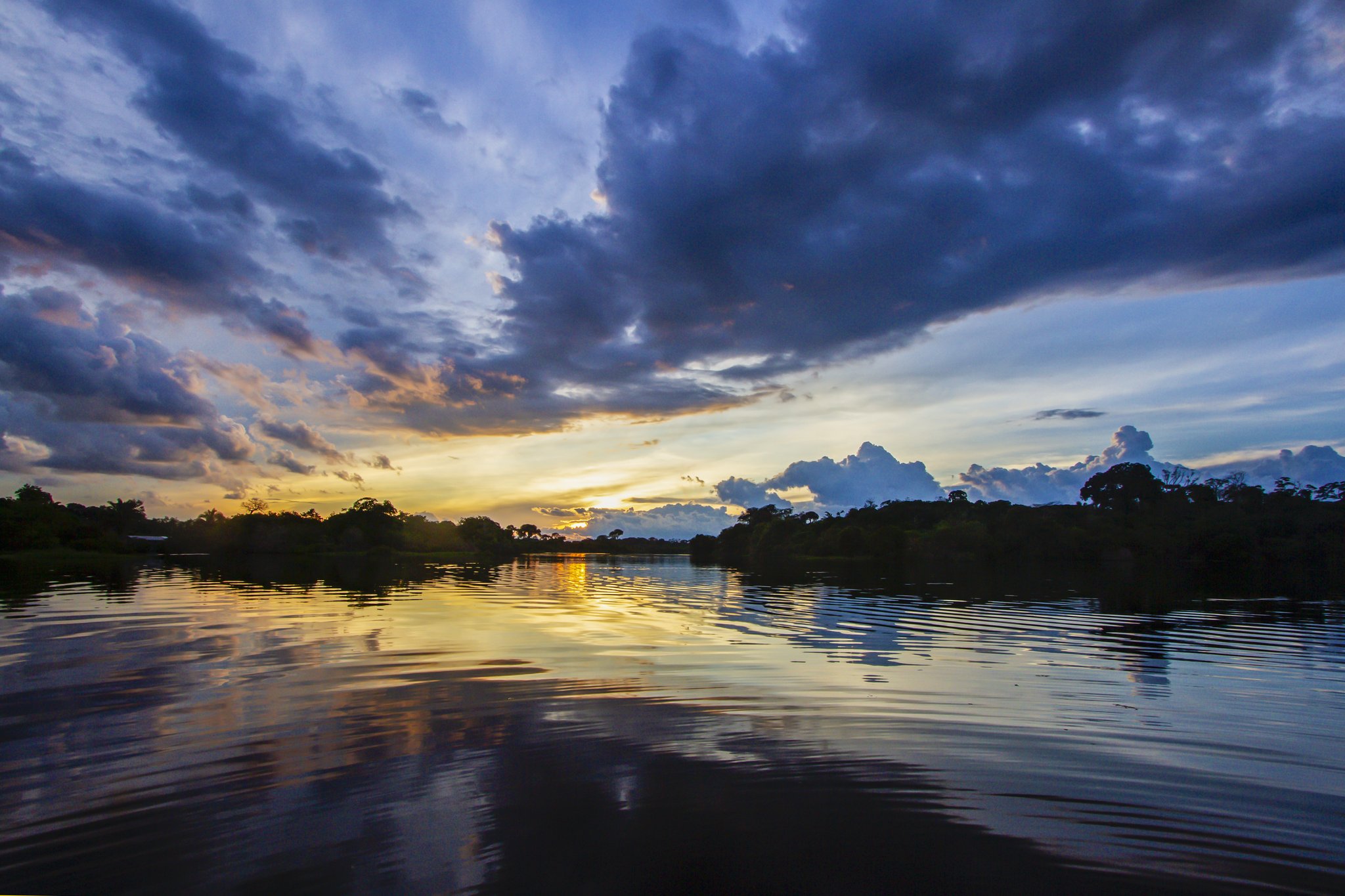 Dramatic Amazon sunset with golden clouds mirrored on calm river water