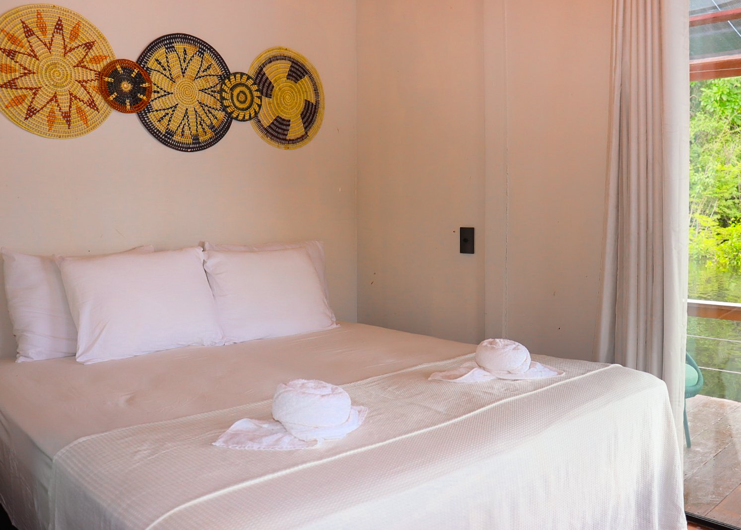 Eco Floating Lodge bedroom with woven indigenous wall plates and a window framing the jungle