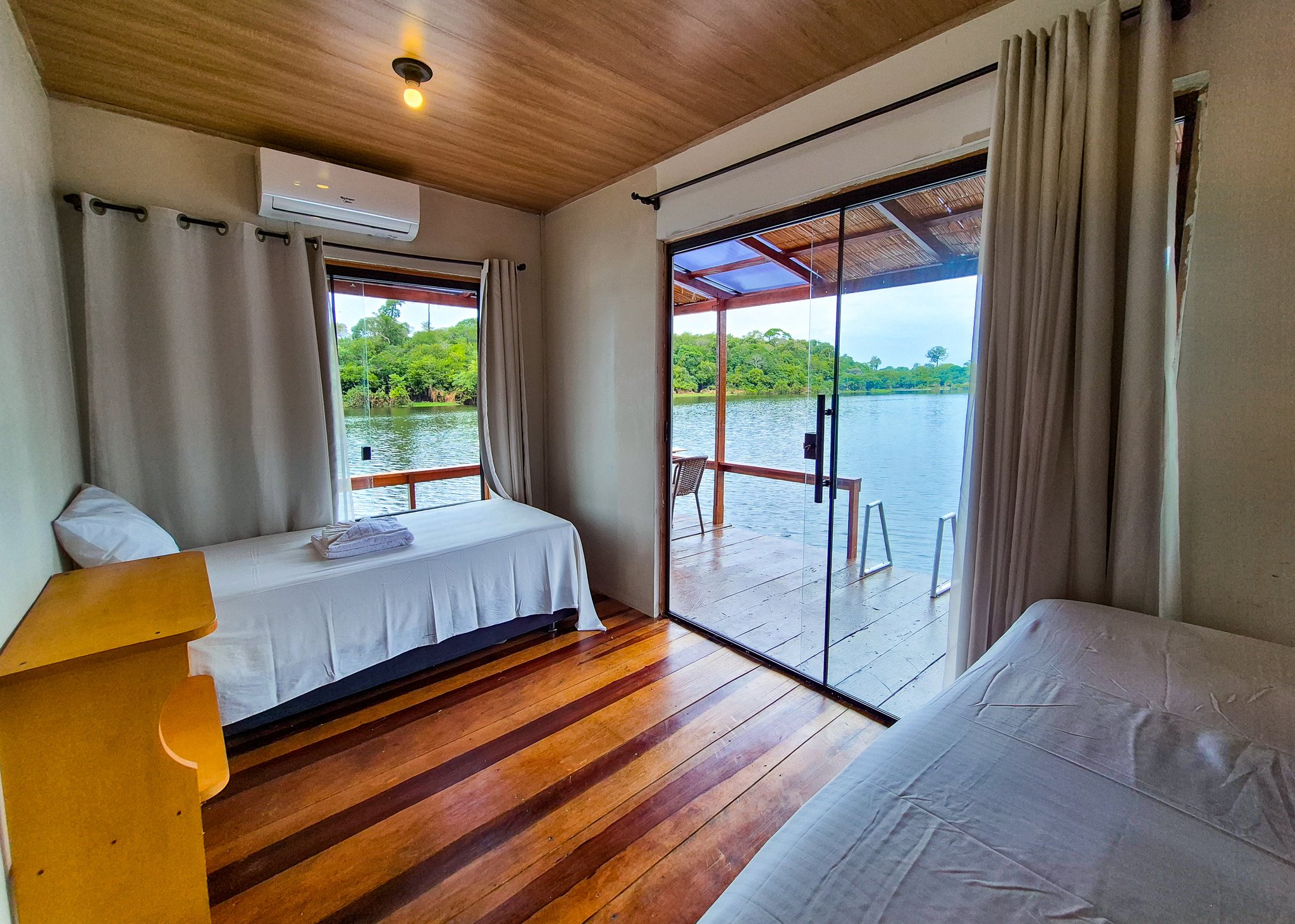 Eco Floating Lodge twin bedroom with sliding doors open onto a deck above the river