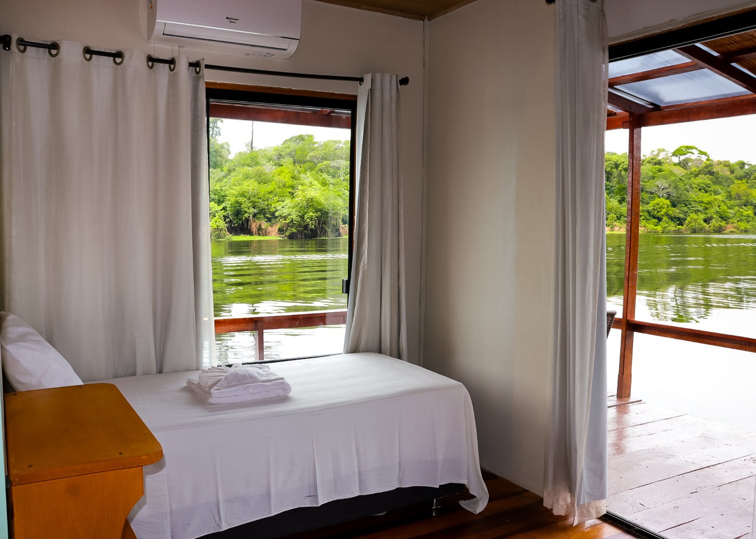 Eco Floating Lodge twin room with a single bed framed by a large window over the green river