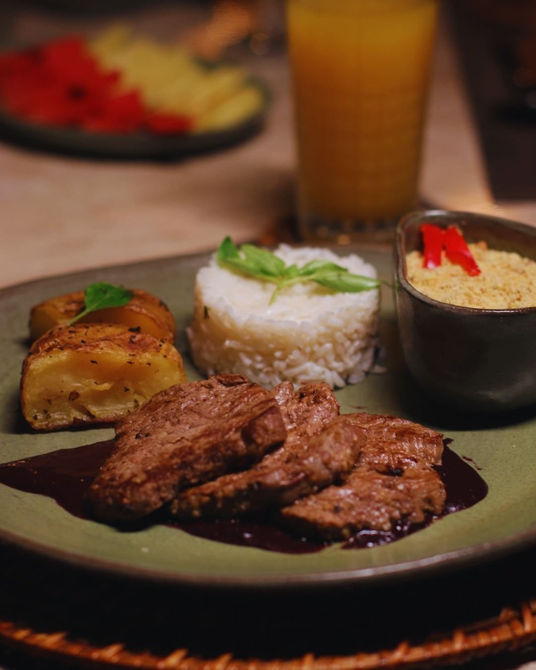 Abendessen in der Juma Amazon Jungle Lodge: gegrillte Rindfleischstreifen in dunkler Sauce, geformter Reis mit frischen Kräutern, gebratene Kartoffelspalten und eine Schüssel Farofa mit roten Paprikastreifen, dazu ein Glas Orangensaft