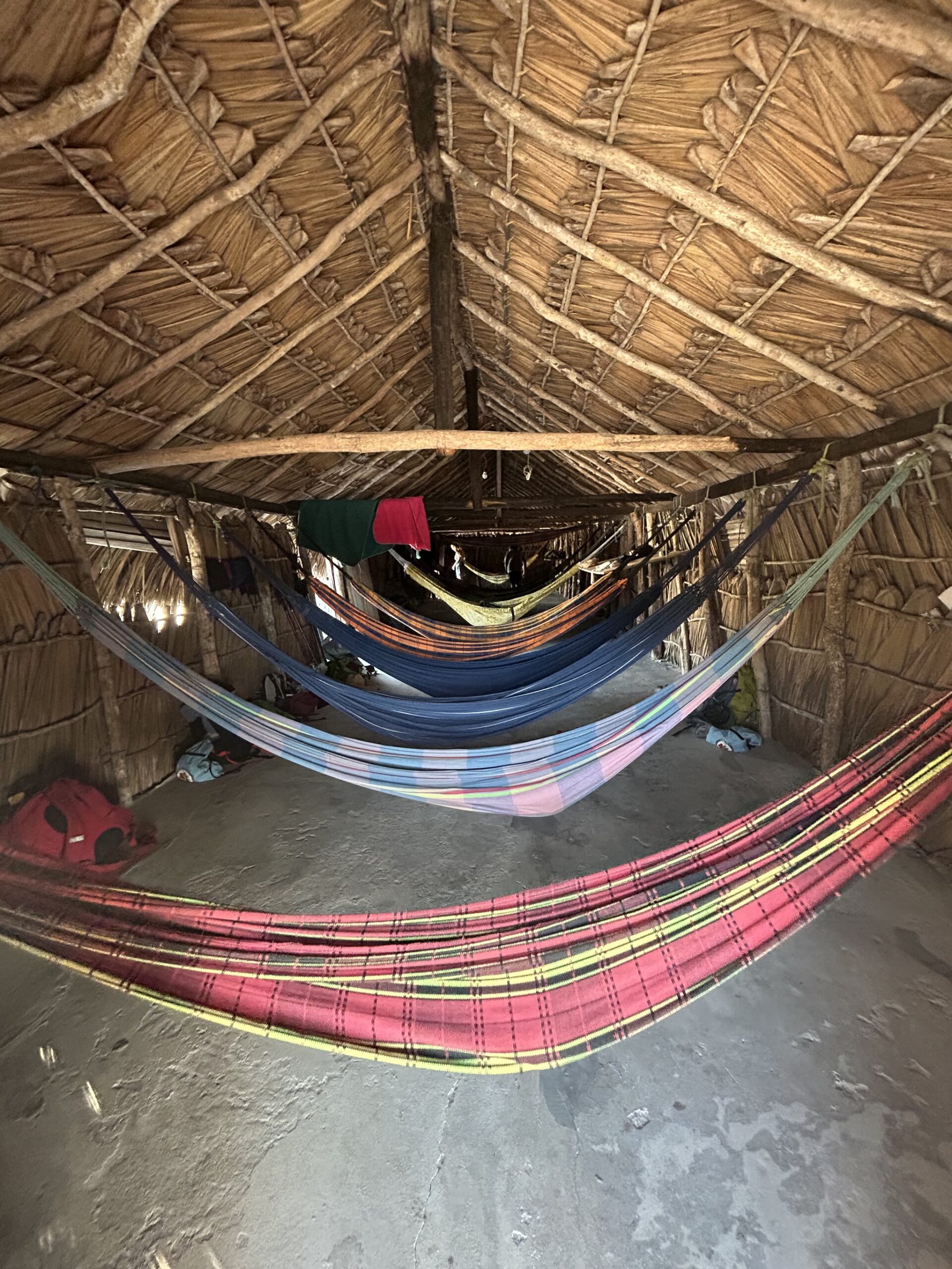 Redes coloridas suspensas em um abrigo rústico de palha, a hospedagem durante a travessia dos Lençóis Maranhenses