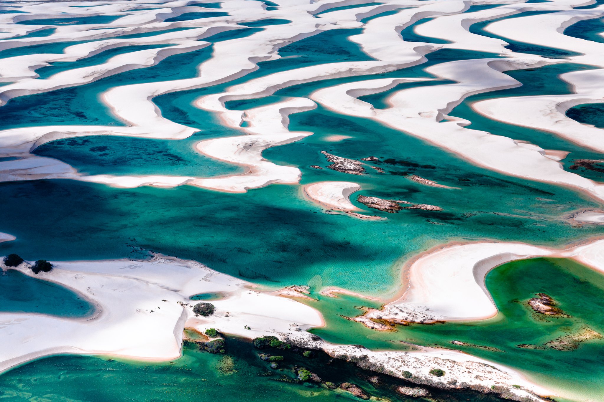 Aerial view of Lençóis Maranhenses trekking terrain showing sweeping white sand dunes interlaced with vivid turquoise and emerald lagoons across the national park