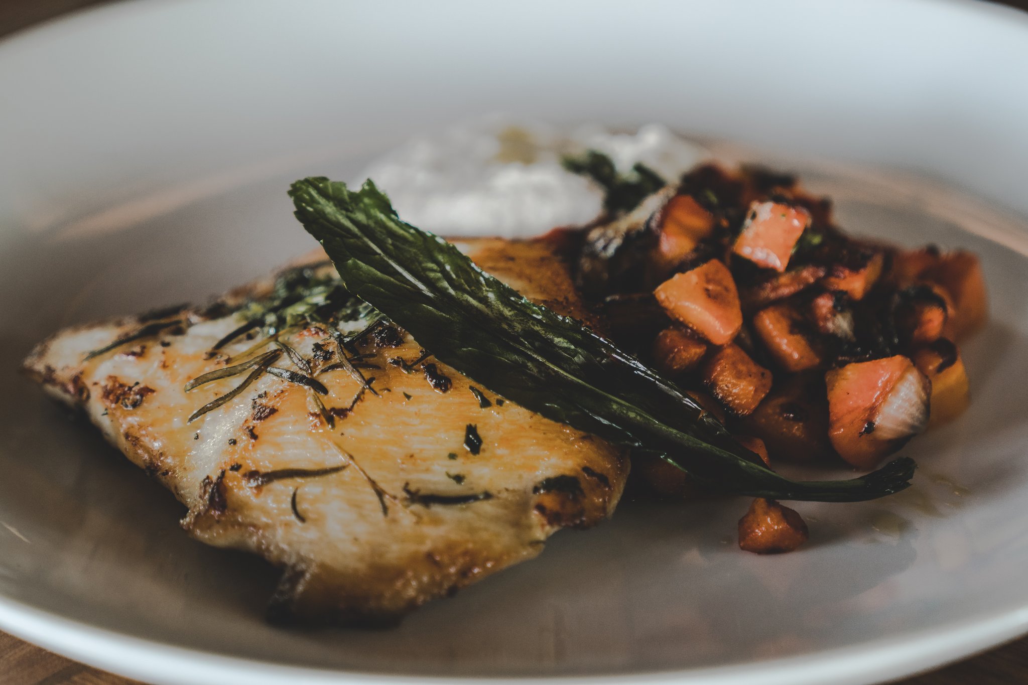 Peixe fresco, ervas aromáticas e sabores da floresta num único prato. Filé de peixe dourado com crosta de ervas servido no restaurante de um lodge de luxo na Amazônia brasileira, acompanhado de folhas refogadas, legumes raiz salteados e um molho cremoso