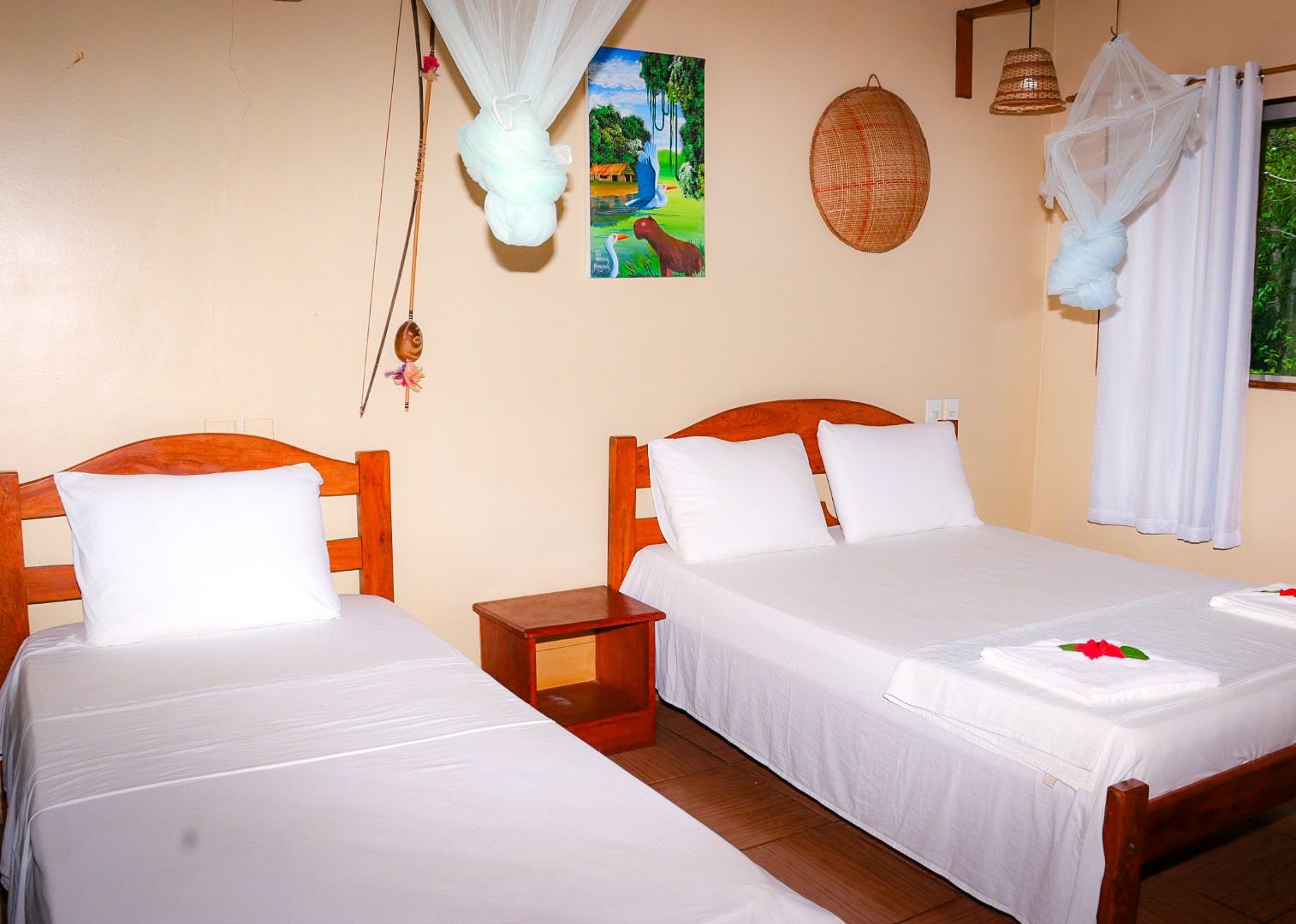 Double and single beds under nets make this comfort bungalow flexible for any group. Masonry comfort bungalow with a double and single bed, mosquito nets and local artwork in the Amazon