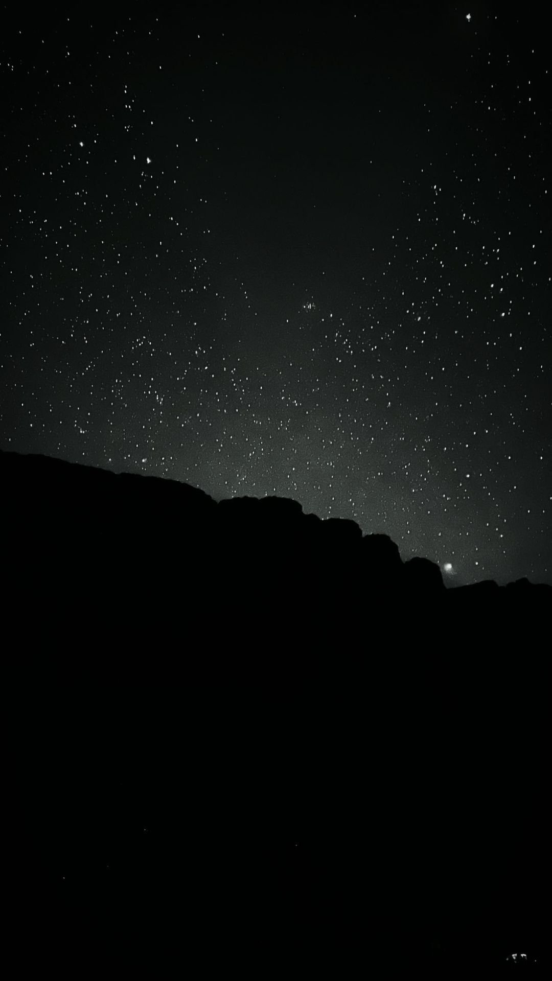 A dense field of stars fills the dark sky above the jagged silhouette of a rocky ridge on the Mount Roraima hike