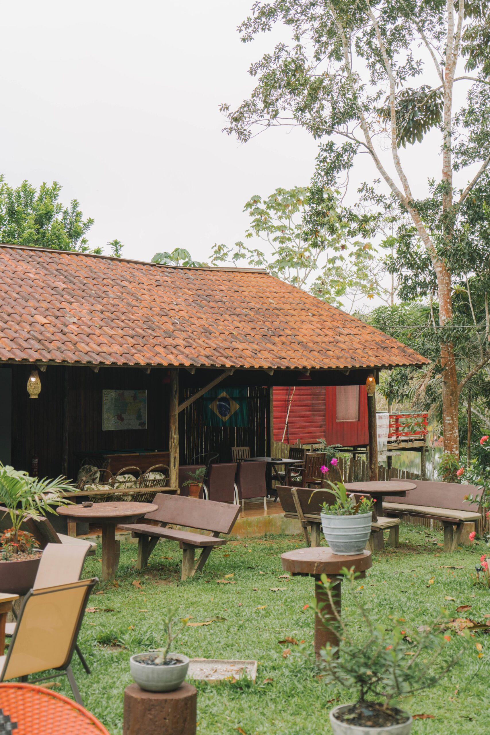 The lodge's open-air lounge invites you to slow down between excursions. Photo: Yuri Panichi Open-air common and dining area of the Amazon Turtle Lodge with a tiled roof and garden seating