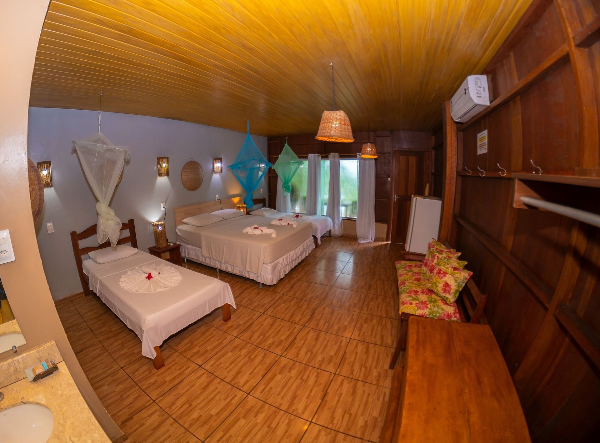 The superior family bungalow easily sleeps the whole group in air-conditioned comfort. Wide view of a superior family bungalow with several beds, mosquito nets and air conditioning in the Amazon