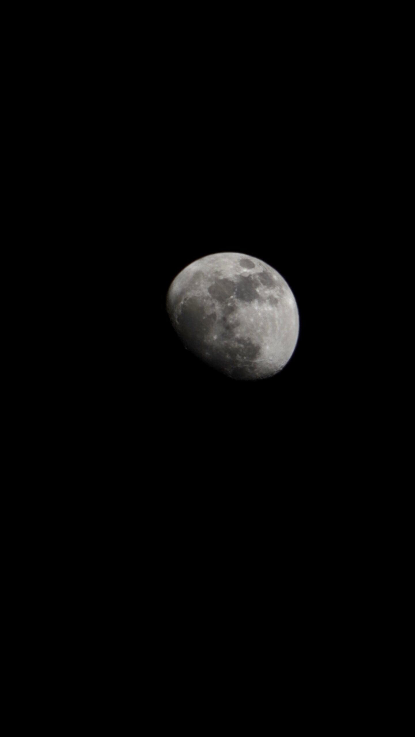 A close-up telephoto shot of a waning gibbous moon against a pitch-black night sky, visible on a trekking in brazil expedition