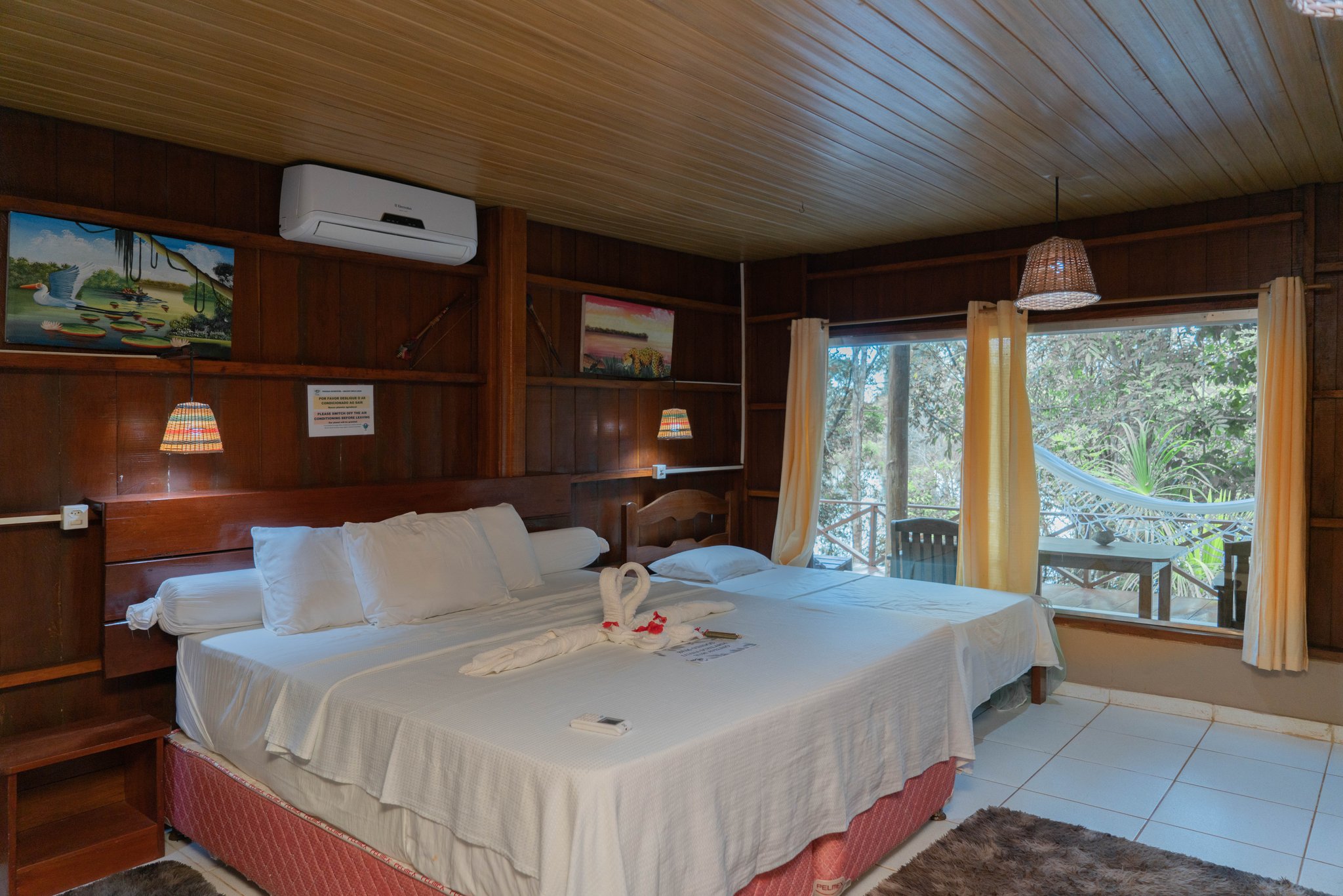 Wood-panelled double room at Turtle Lodge with a hammock-strung balcony overlooking the forest