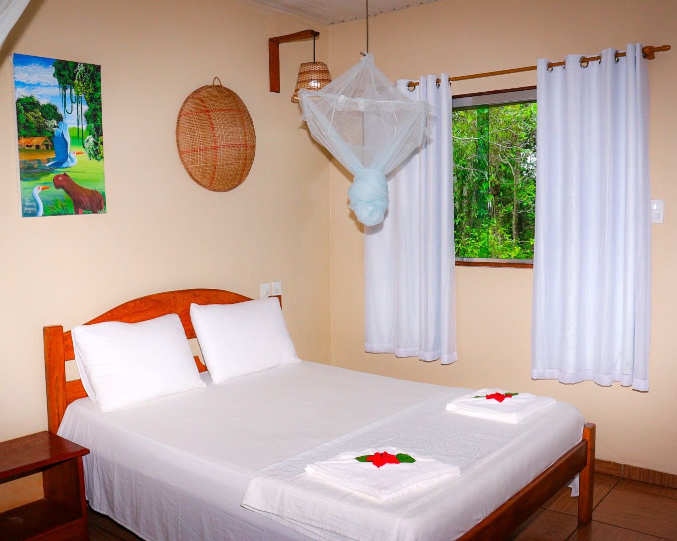 Turtle Lodge double room with a draped mosquito net and a window opening onto green jungle
