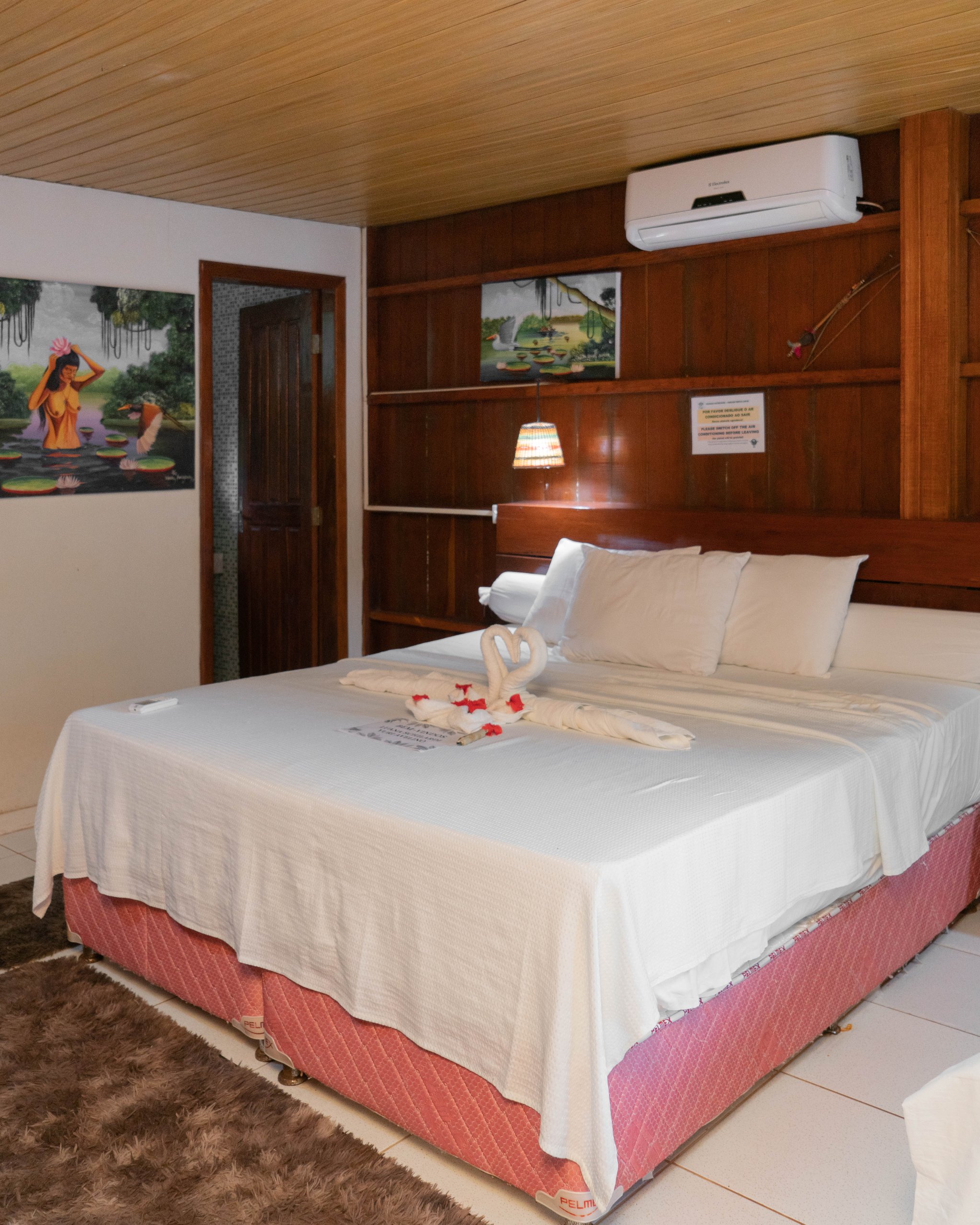 Turtle Lodge double room with white linens, regional folk paintings and a swan towel detail