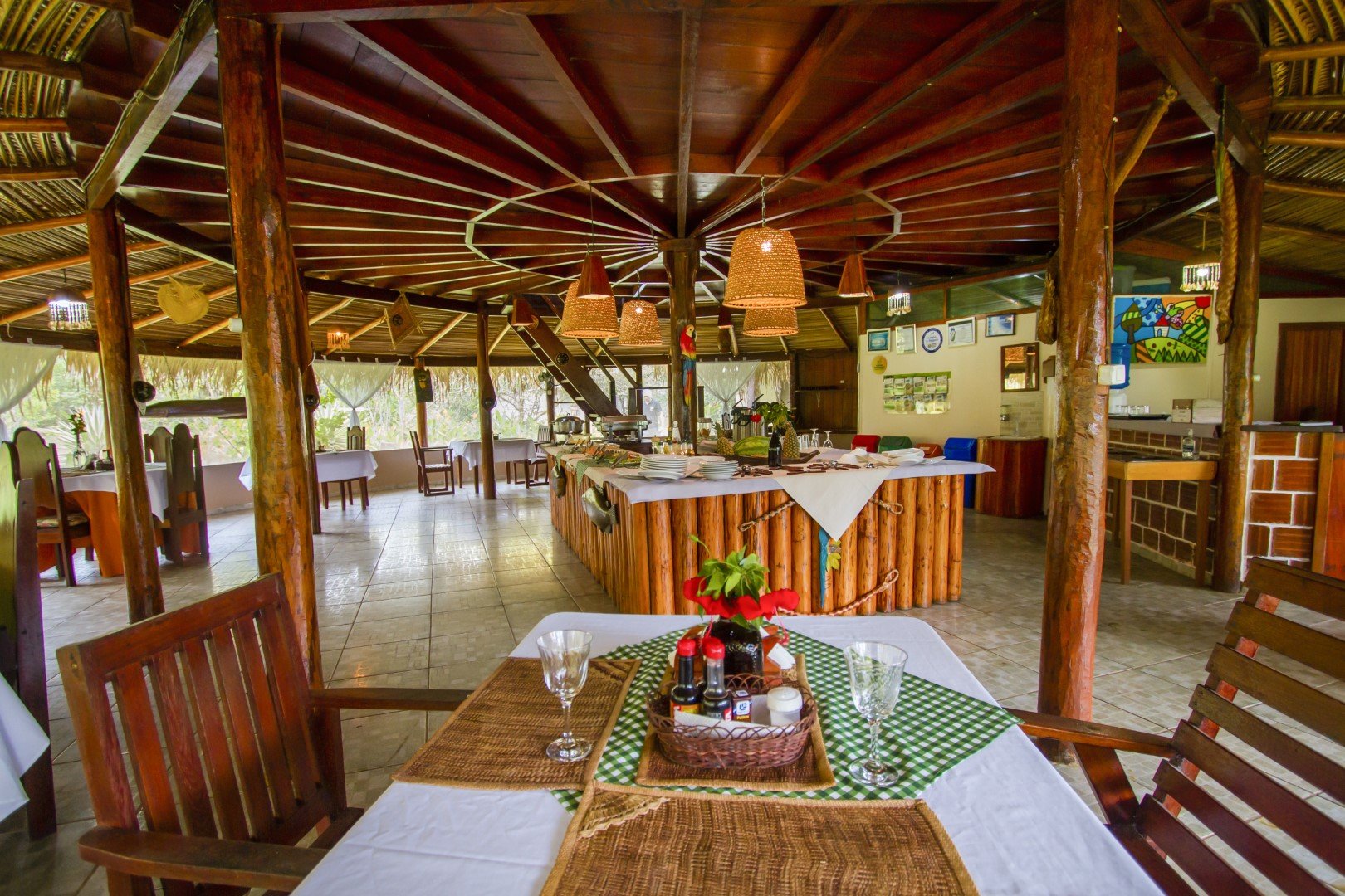 Meals are served in the airy thatched dining hall at the heart of the lodge. Spacious wooden thatched-roof dining hall with set tables at the Amazon Turtle Lodge