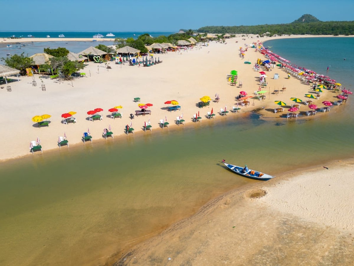 Aerial view of an Amazon river beach with colorful umbrellas and tables on white sand