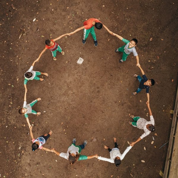 Aerial view of children holding hands in a circle in an Amazon riverside community