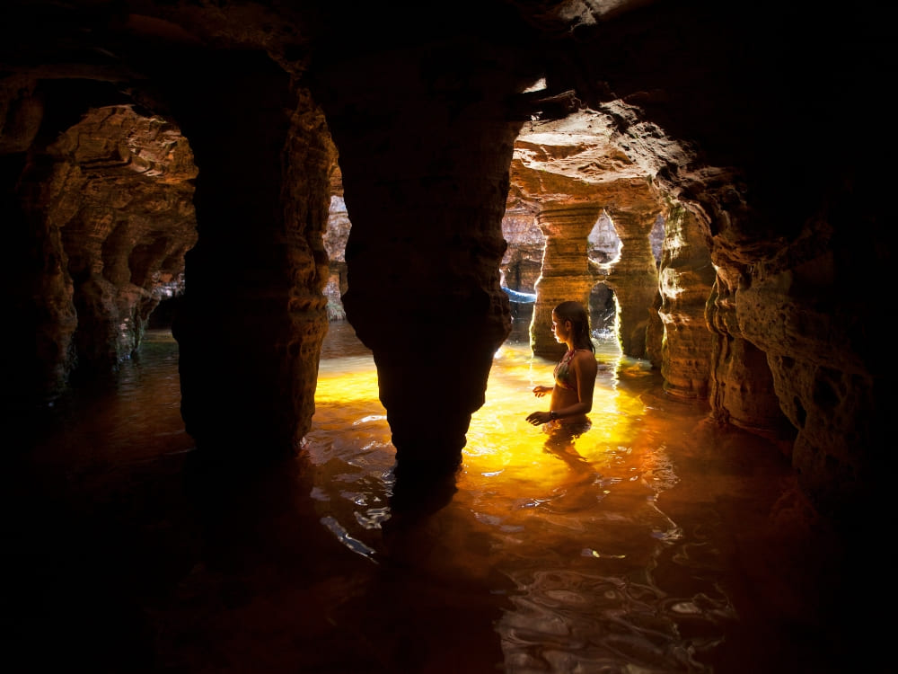 A swimmer in the golden natural pool inside a cave at Mount Roraima