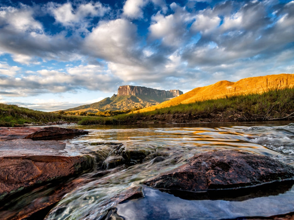 The Kukenán tepui next to Mount Roraima reflected in a river at golden hour