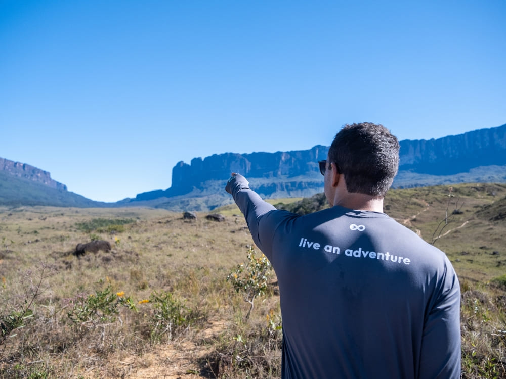 A hiker pointing toward the Kukenán tepui view from Mount Roraima
