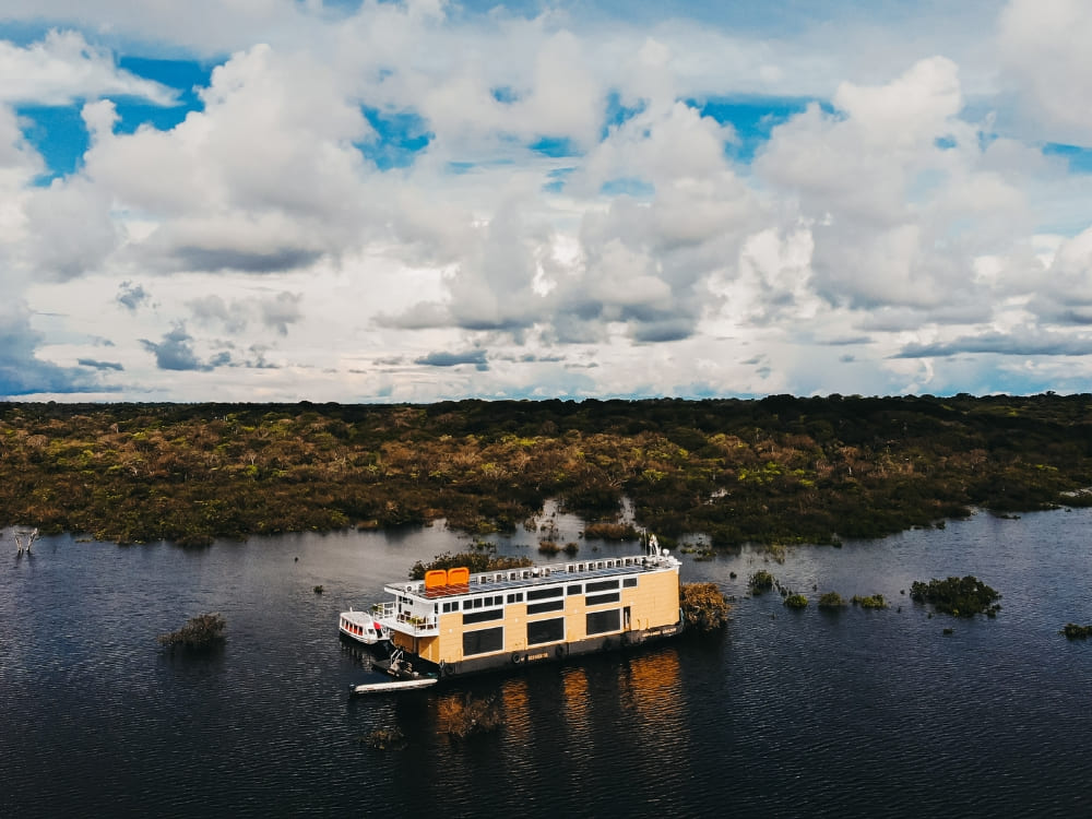 Veduta aerea del battello di lusso Untamed ormeggiato sul Rio Negro, circondato dalla foresta amazzonica allagata.