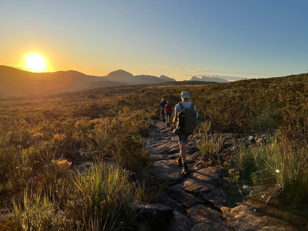 Eine Gruppe wandert bei Sonnenaufgang über einen Steinpfad auf dem Vale do Pati Trek in der Chapada Diamantina, Brasilien.