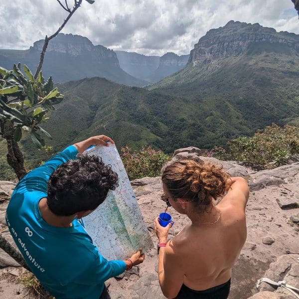 Zwei Wanderer studieren eine Wanderkarte auf einem Felsen über den Canyons des Vale do Pati, Chapada Diamantina, Brasilien.