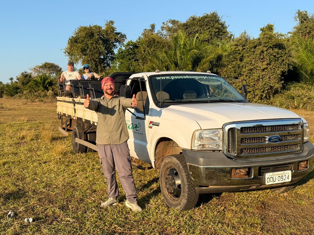 El guía de la familia junto a la camioneta abierta de safari