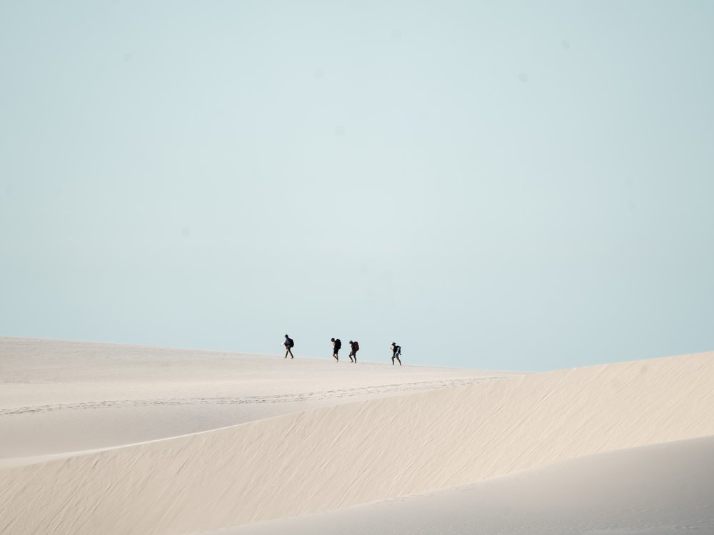 Petit groupe de randonneurs traversant les dunes de sable blanc des Lençóis Maranhenses