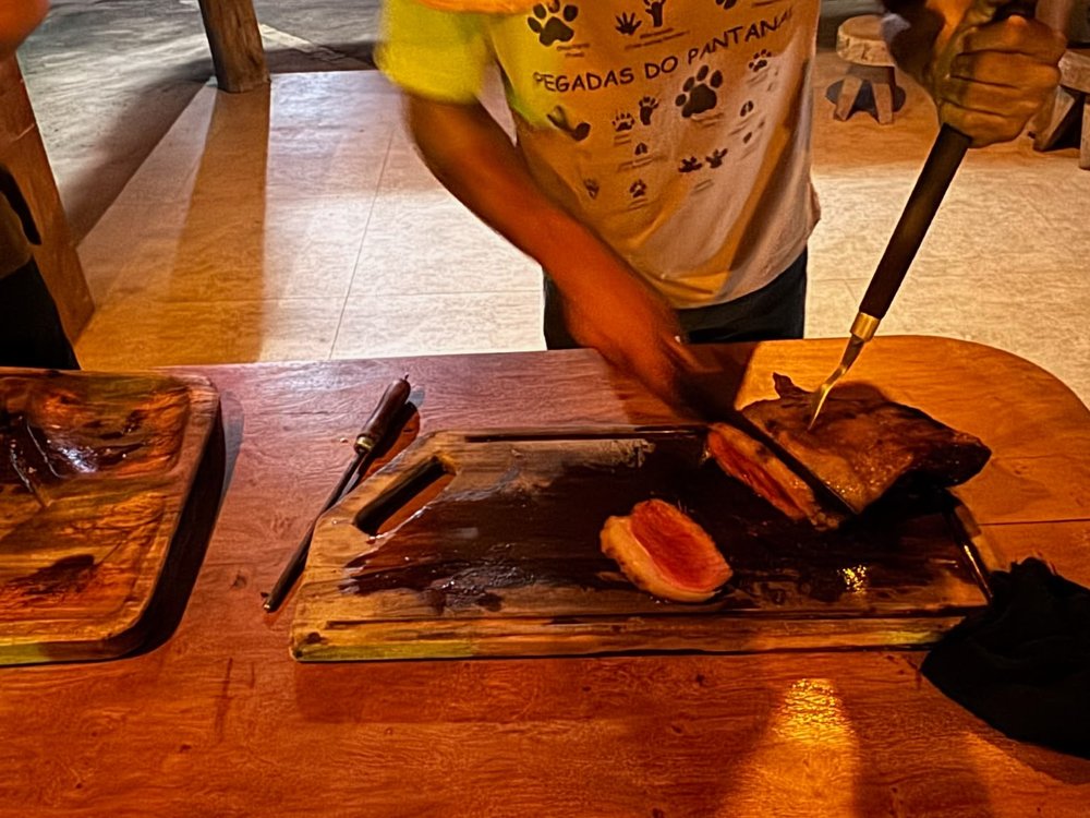 El cocinero de la posada corta carne asada en una tabla de madera
