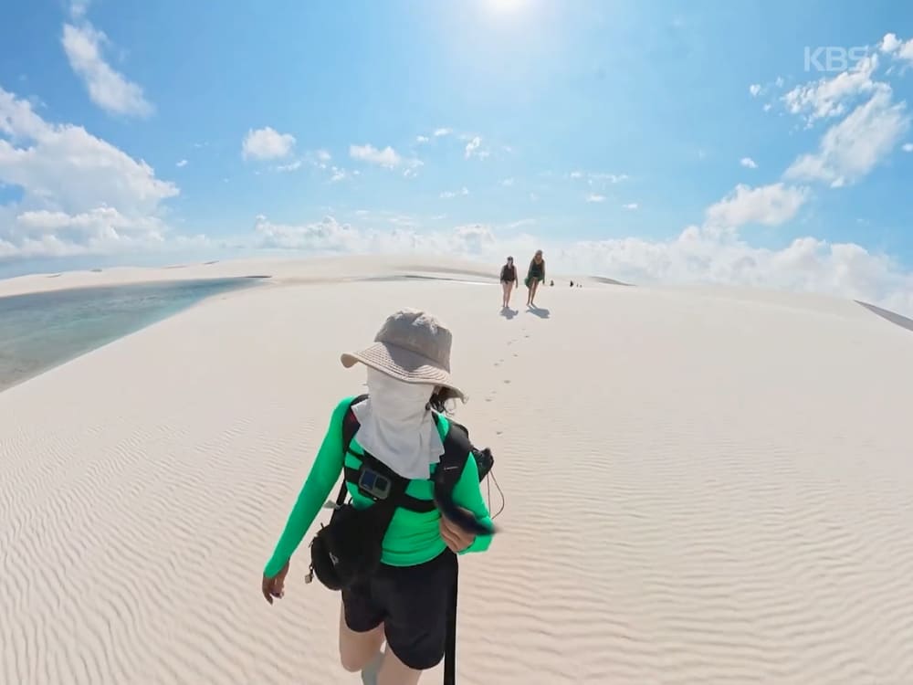 Jihee Yeon trekking across the white dunes of Lençóis Maranhenses, with two hikers ahead