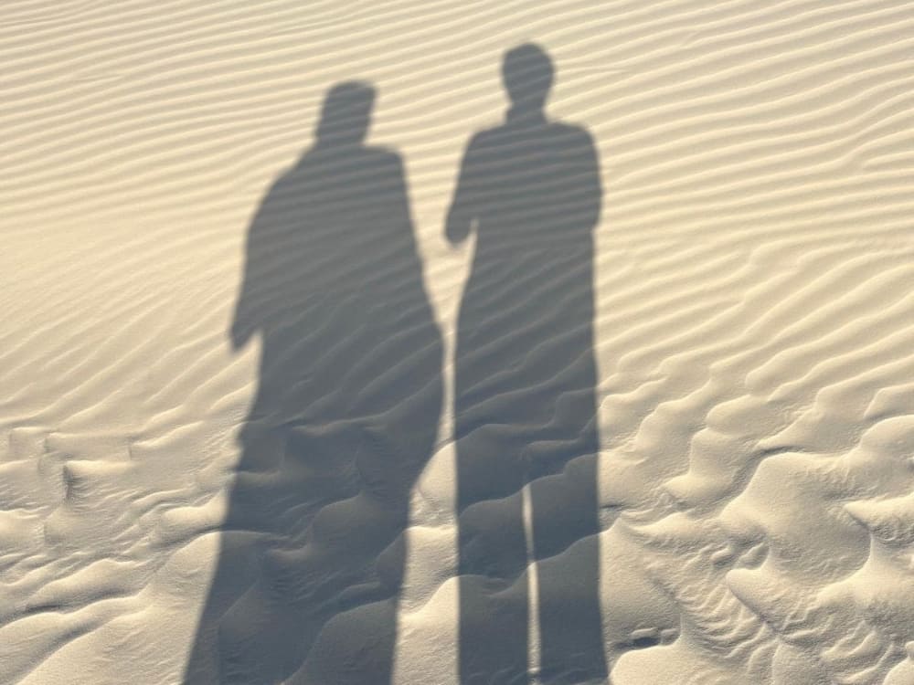 Ombres de Maja et Slobodan projetées sur le sable blanc ridé des Lençóis Maranhenses