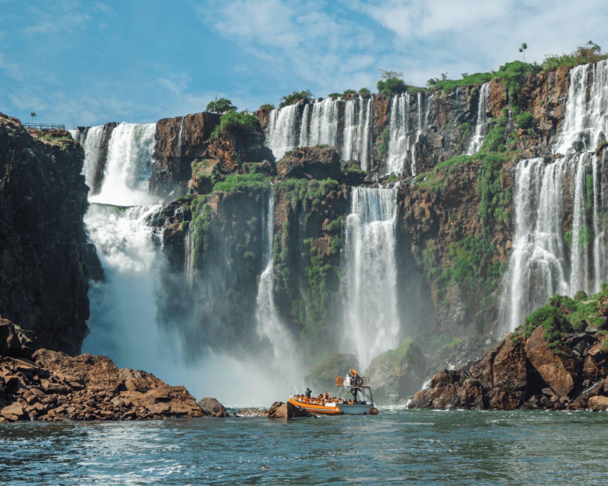 Excursion en bateau s'approchant du pied des chutes d'Iguazu sous un ciel bleu