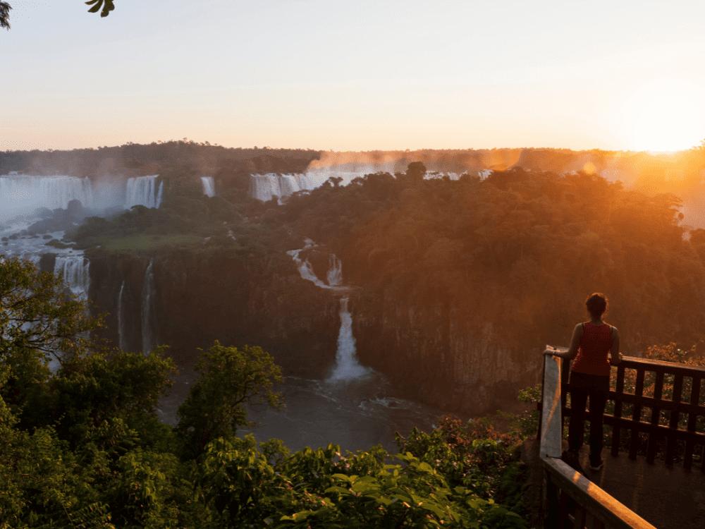 Voyageuse regardant le coucher de soleil sur les chutes d'Iguazu depuis un belvédère