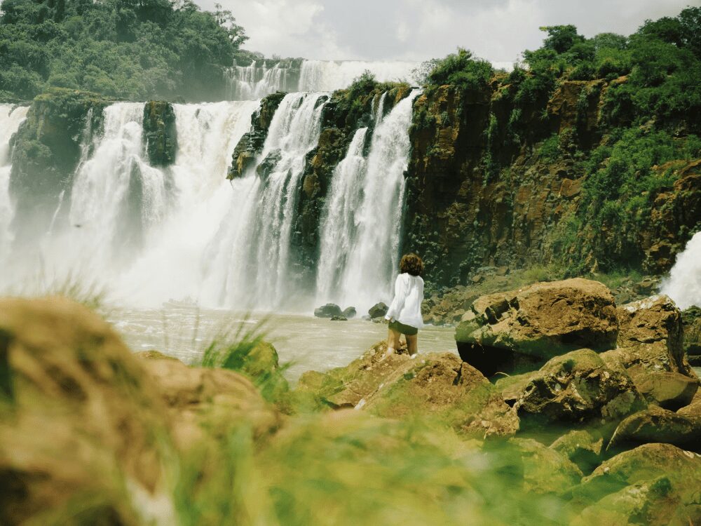 Voyageuse debout sur les rochers au pied des cascades des chutes d'Iguazu